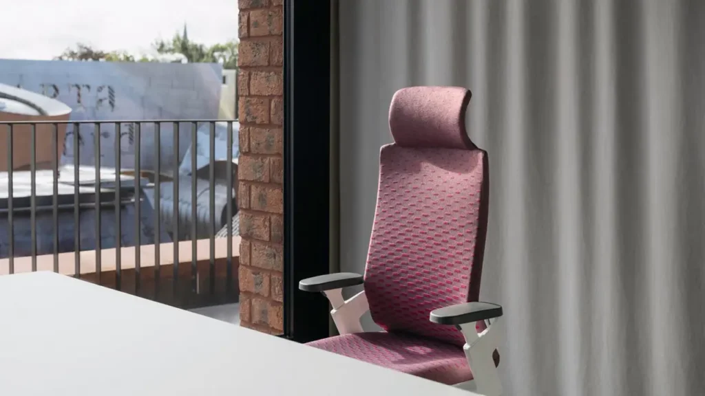 Moderner Wilkhahn ON Casual Bürostuhl in Rot mit hoher Rückenlehne und Kopfstütze, platziert an einem Schreibtisch vor einer Fensterfront mit Vorhängen.