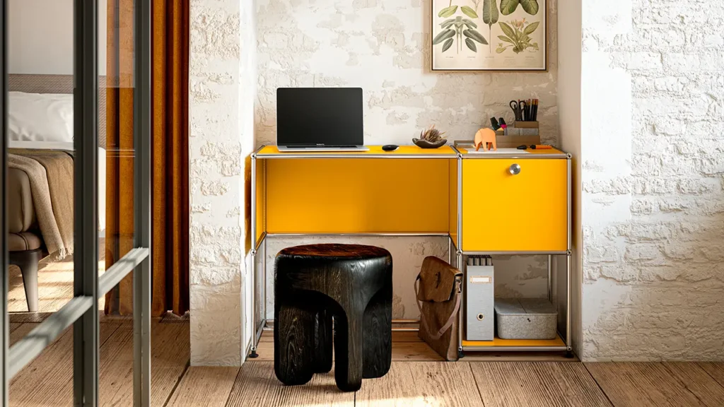 Kompaktes USM Haller Homeoffice in Gelb in einer Nische mit Ziegelwand, Laptop und Holzstuhl – platzsparendes Arbeitsplatzdesign von unitedspaces.