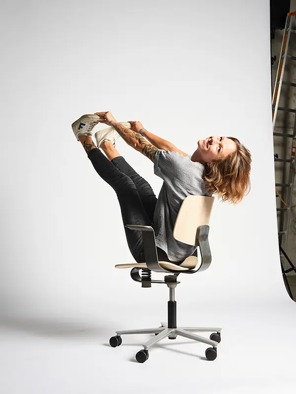 Wilkhahn WiChair – ergonomische Bewegungsfreiheit mit Leichtigkeit erleben Person demonstriert die flexible Beweglichkeit des Wilkhahn WiChair durch eine dynamische Sitzpose auf dem minimalistischen Drehstuhl.