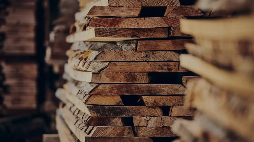 Gestapelte Holzbretter in warmem Licht – Symbol für die handwerkliche Fertigung und Materialqualität bei COR Möbel.