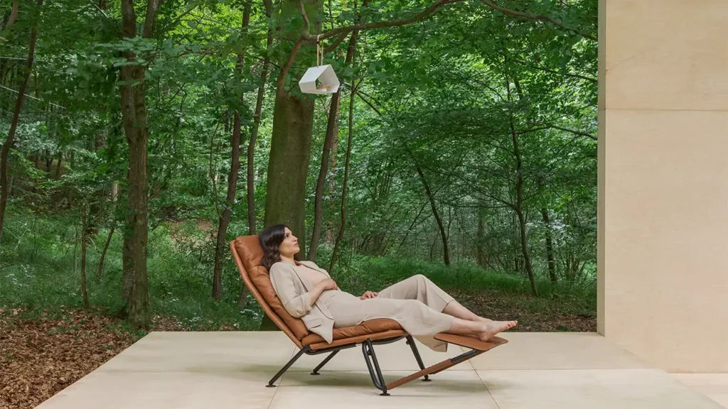 Frau entspannt auf einem Leder-Relaxsessel von Prostoria auf einer Terrasse im Grünen – modernes Möbeldesign, inspiriert von Natur und Ruhe.