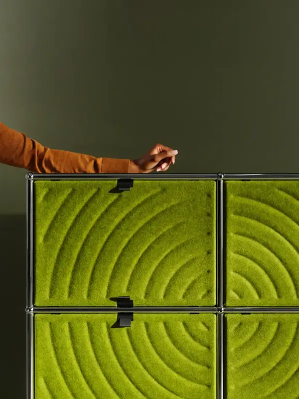 Grüne USM Haller Soft Panels in einem modularen Regalsystem, montiert als textile Akustikflächen mit magnetischer Befestigung