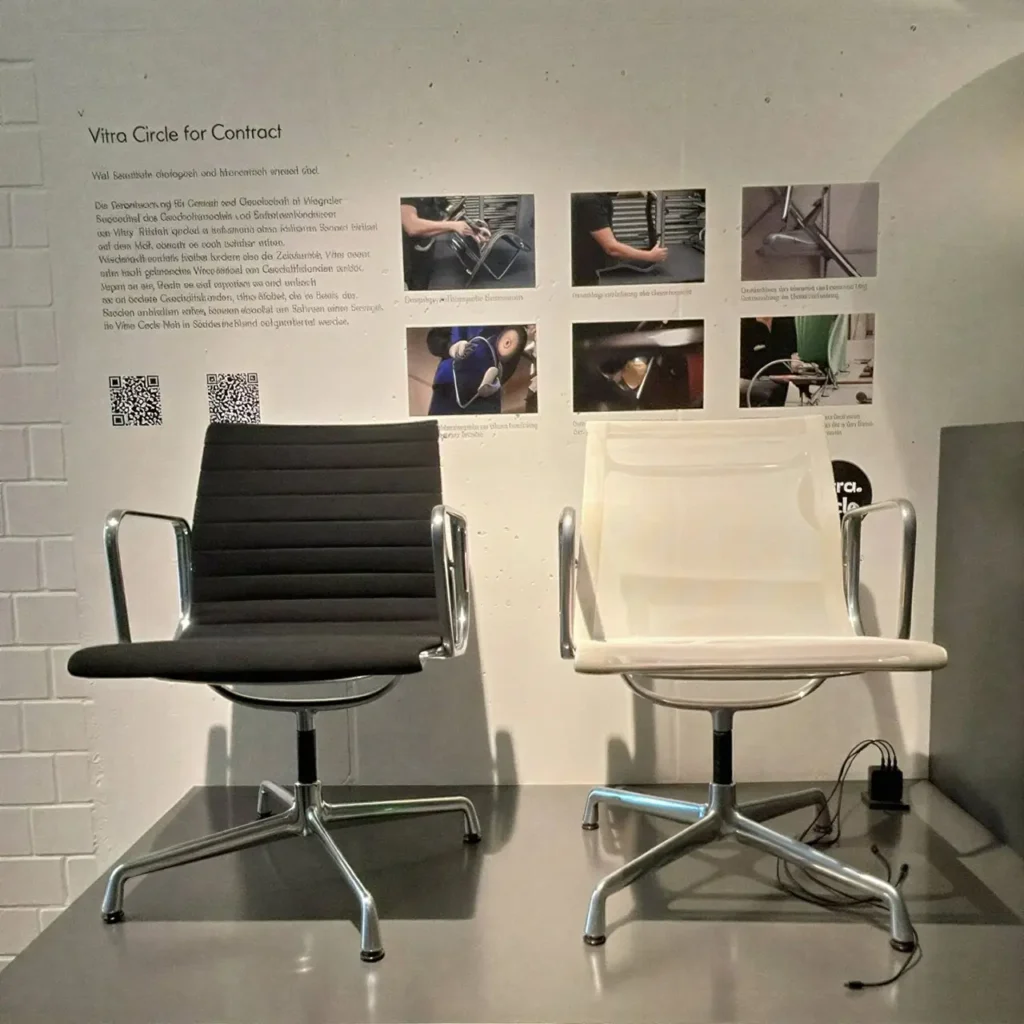 Zwei Vitra Aluminium Chairs in Schwarz und Weiß vor einer Vitra Circle Infowand bei unitedspaces in Berlin.